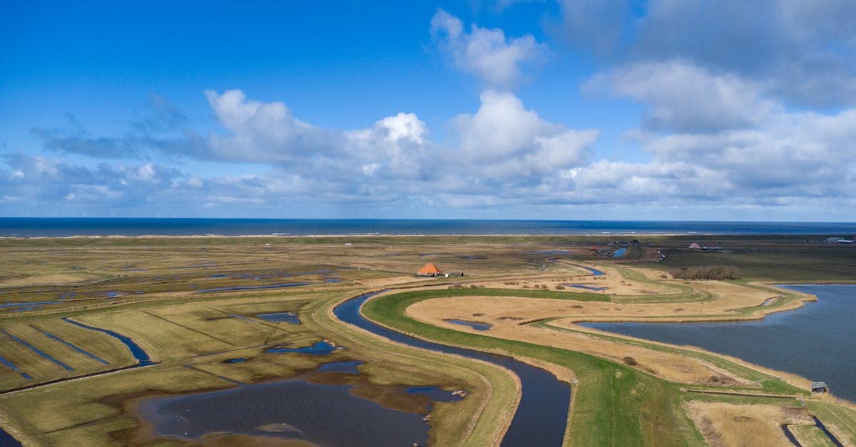 Luchtfoto van groene Nederlandse kustlijn en polders, ideaal voor een goedkope vakantie dichtbij huis.