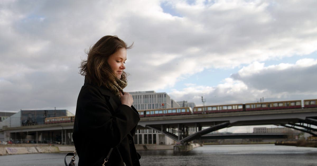 Junge Frau beim Alleinreisen lächelt während Winterspaziergang an Berliner Brückenanlage