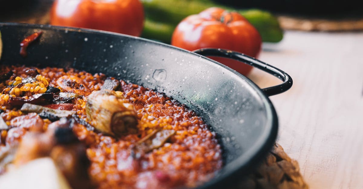 Freshly made paella in a pan with tomatoes and greens, an essential dish when exploring what to eat in Spain