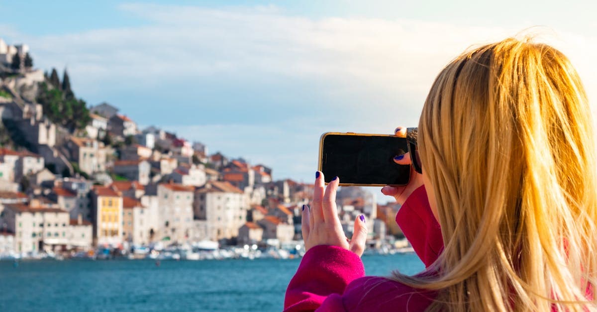 Woman photographing the Šibenik waterfront in Croatia, comparing eSIM Europe costs versus carrier roaming charges