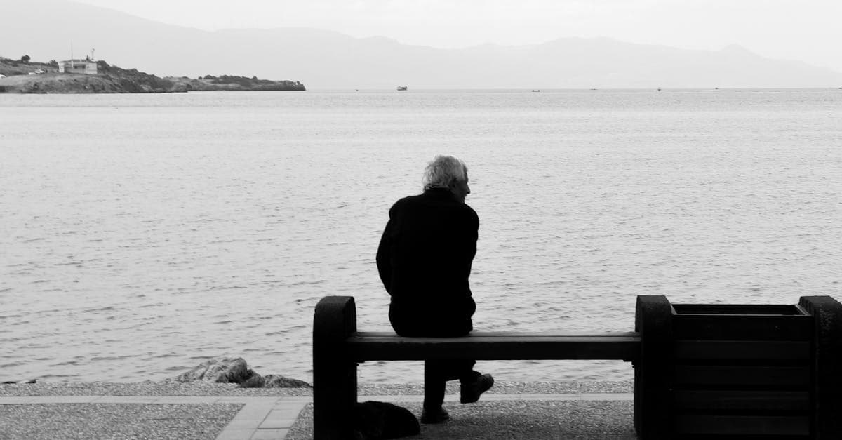 Äldre person sitter ensam vid havet – viktig påminnelse om pension vid arbete utomlands