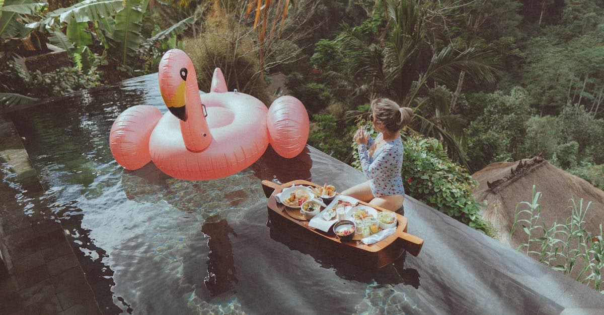 Mujer disfrutando del desayuno en piscina infinita con flamenco inflable en resort de Bali, opciones para todos los presupuestos