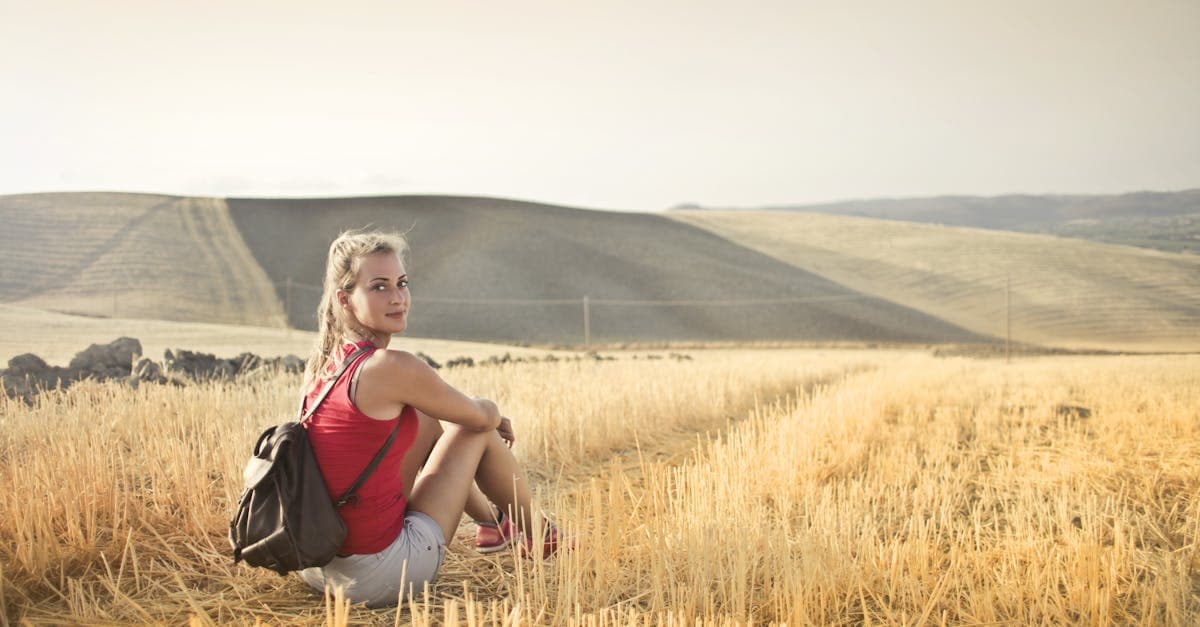 Woman relaxing in a sunlit countryside hayfield, reflecting on her solo India travel journey