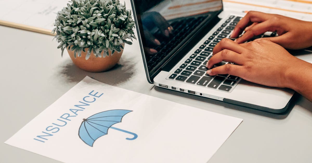 Traveller researching backpacker insurance options on a laptop with policy documents beside them