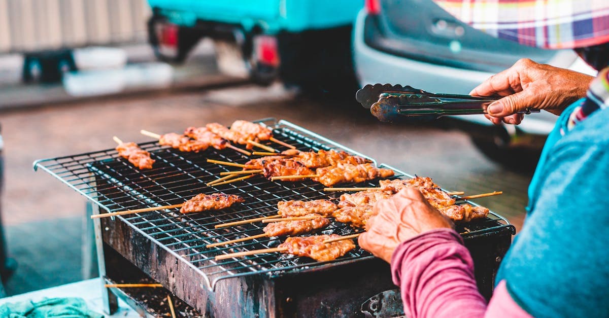 Skewered meats grilling at a street food Bangkok stall, among the city's most iconic dishes