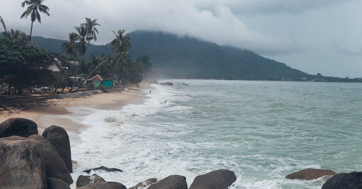 Bølger slår ind mod tropisk strand på Koh Samui under regnsæsonen i Thailand.