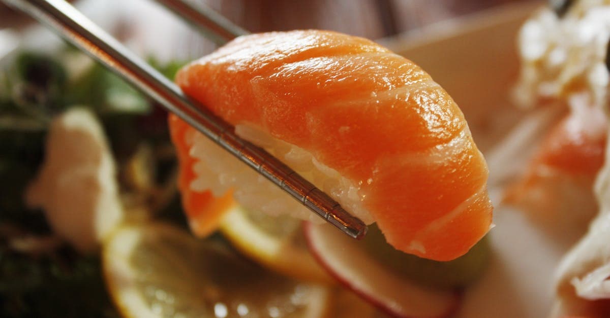 Chopsticks holding salmon nigiri sushi, a budget-friendly dish highlighting what to eat in Japan
