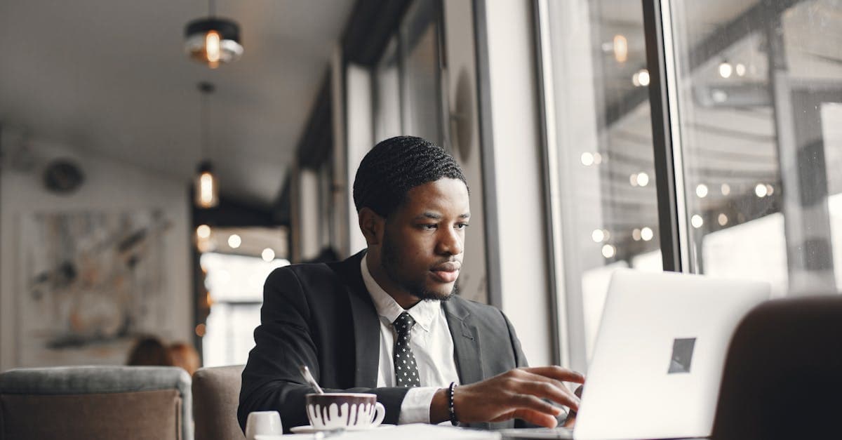 Şık bir kafede dizüstü bilgisayarıyla çalışan iş insanı, aylık Superbox taşınabilir wifi paket fiyatlarına bakıyor.