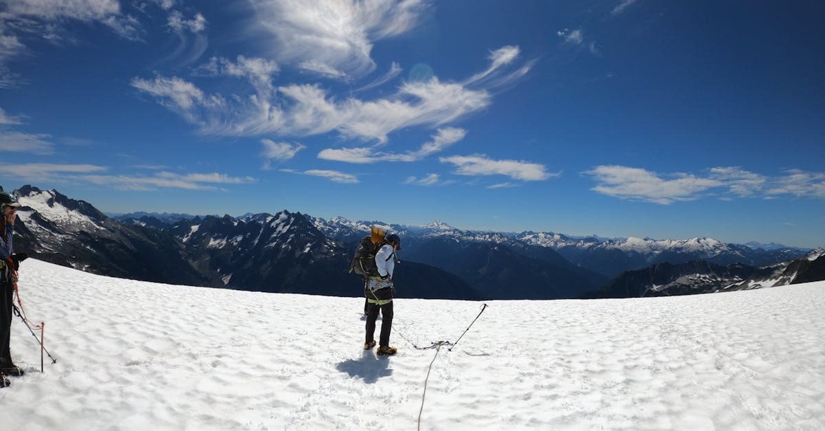 Two mountaineers on a snow-covered peak, representing adventure sports that can be added to a backpacker insurance policy