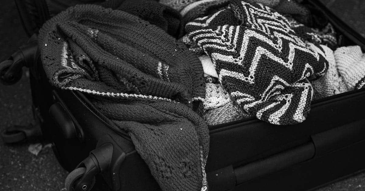 Valigia aperta con maglioni lavorati a maglia: scopri cosa non mettere in valigia a mano secondo le regole 2026