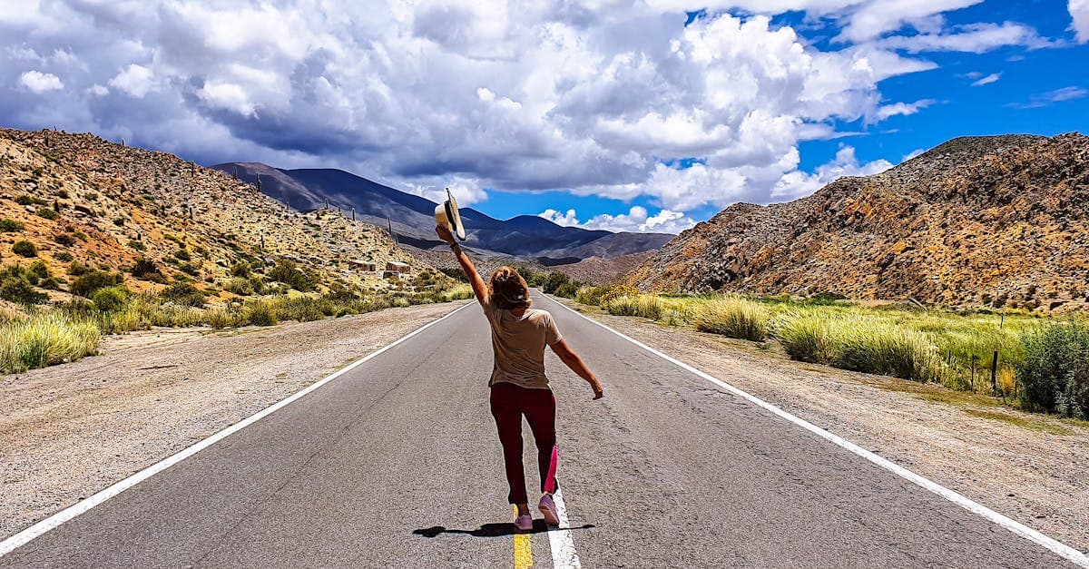 Vrouw rent vrolijk over een bergweg, de beste bestemmingen voor alleen op vakantie in 2026.