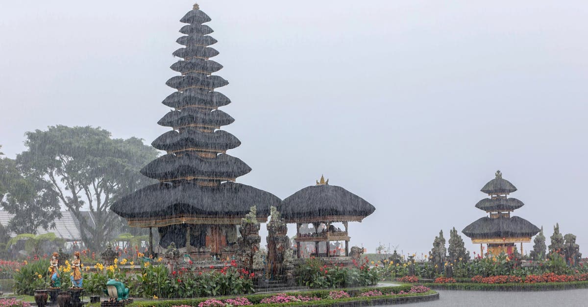 Wet season bali weather: Ulun Danu Temple with vibrant flowers amid tropical rainfall and vegetation.