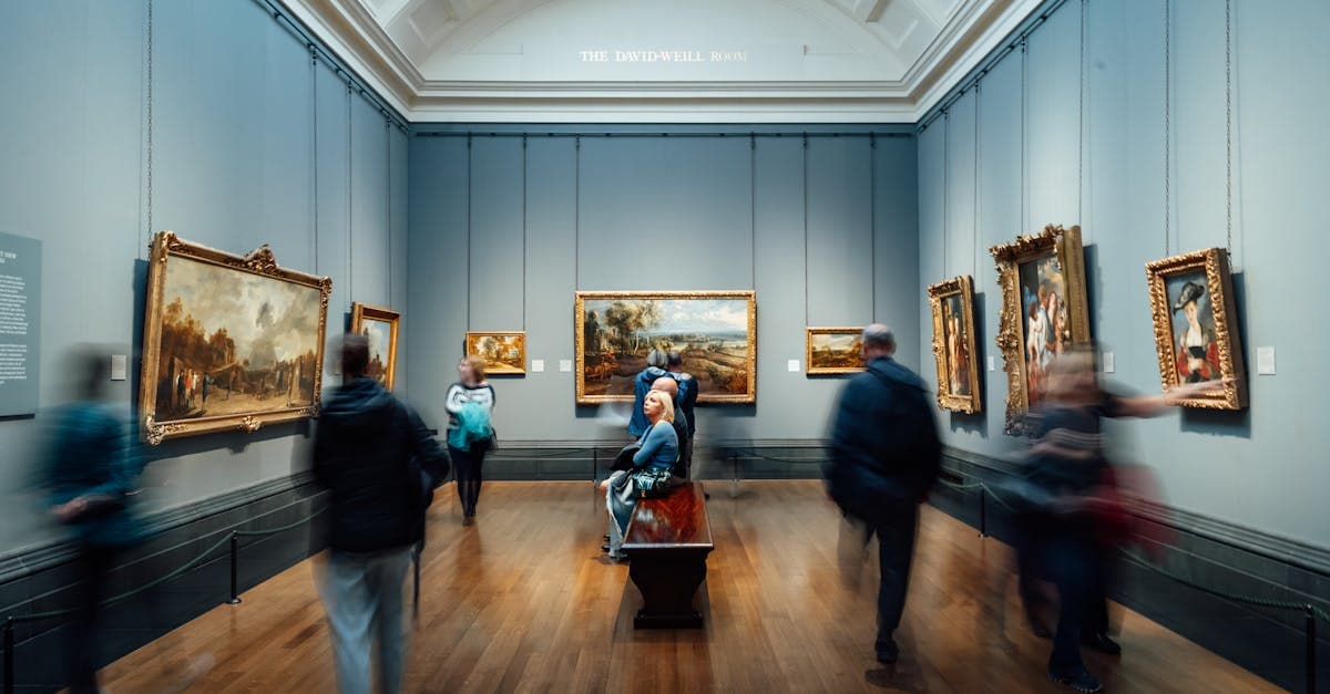 Visitantes admirando pinturas en una galería de arte en Inglaterra, descubriendo la cultura al viajar sola.