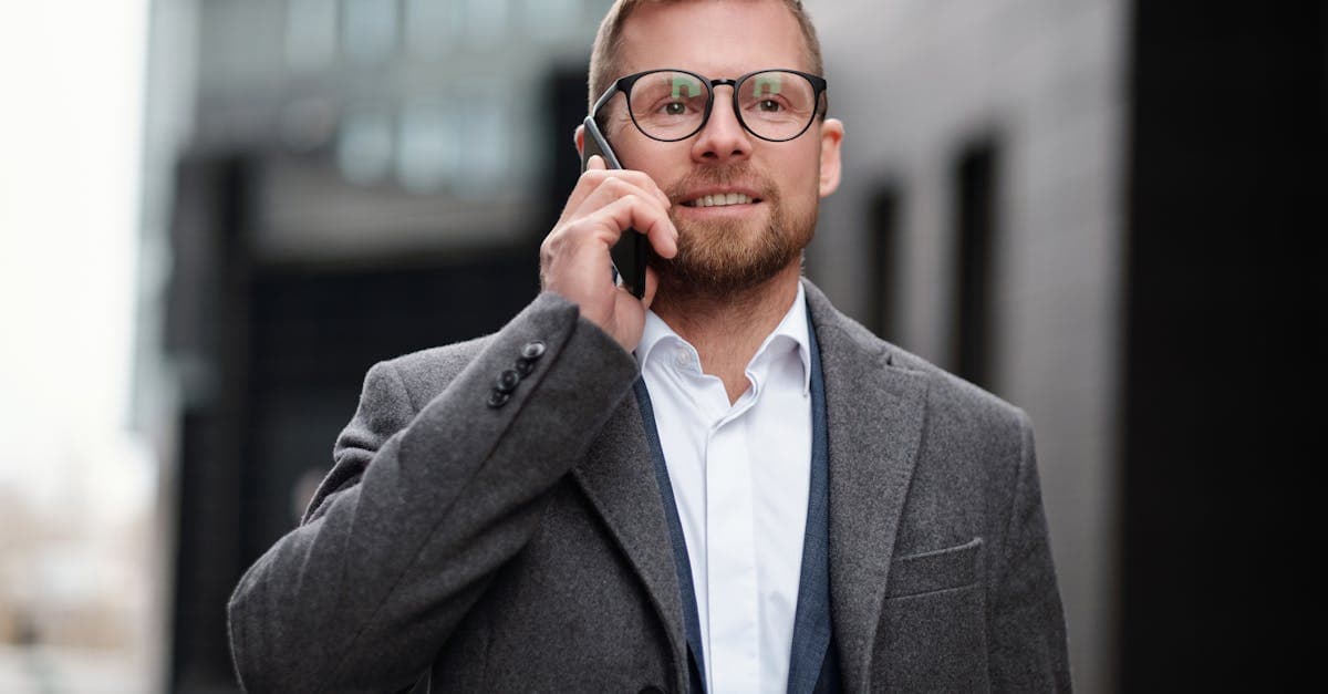 Professionista in cappotto grigio parla al telefono all'aperto: la tessera sanitaria europea è completamente gratuita