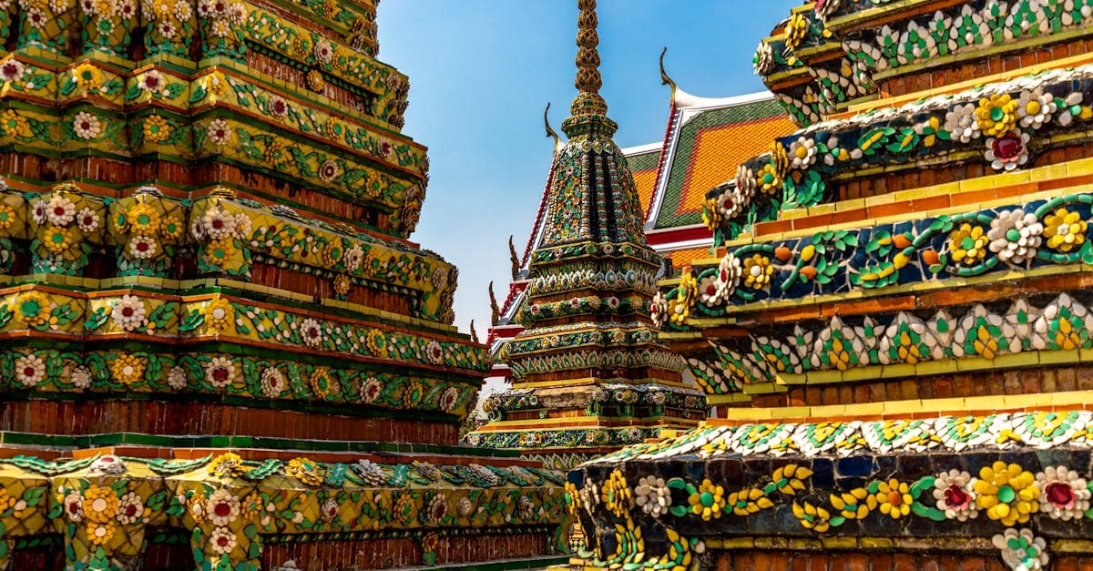 Ornate golden chedis of Wat Pho temple complex in Bangkok, Thailand under a clear blue sky