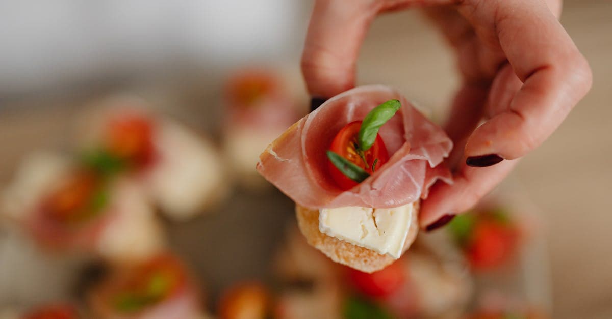Hand-held pintxos topped with cured meat and cheese, showing the difference between tapas and pintxos in Spain