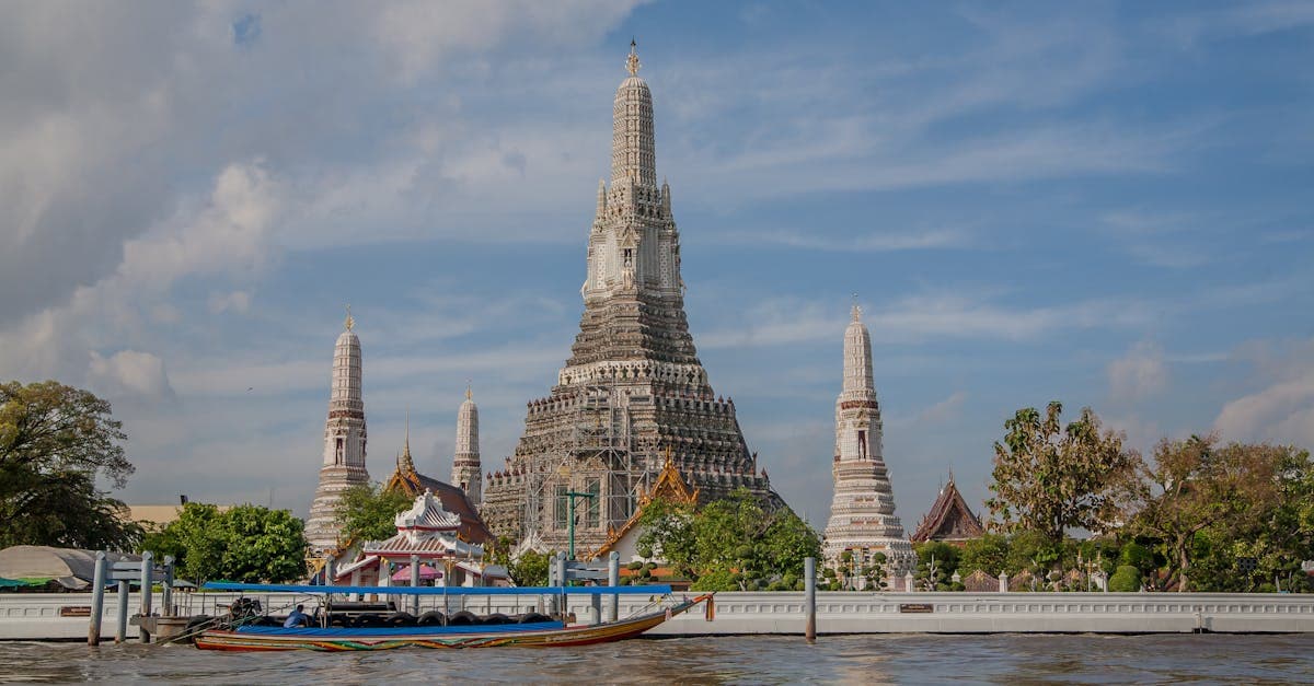 Wat Arun temple beside the Chao Phraya River at dusk, one of the iconic places to visit in Thailand