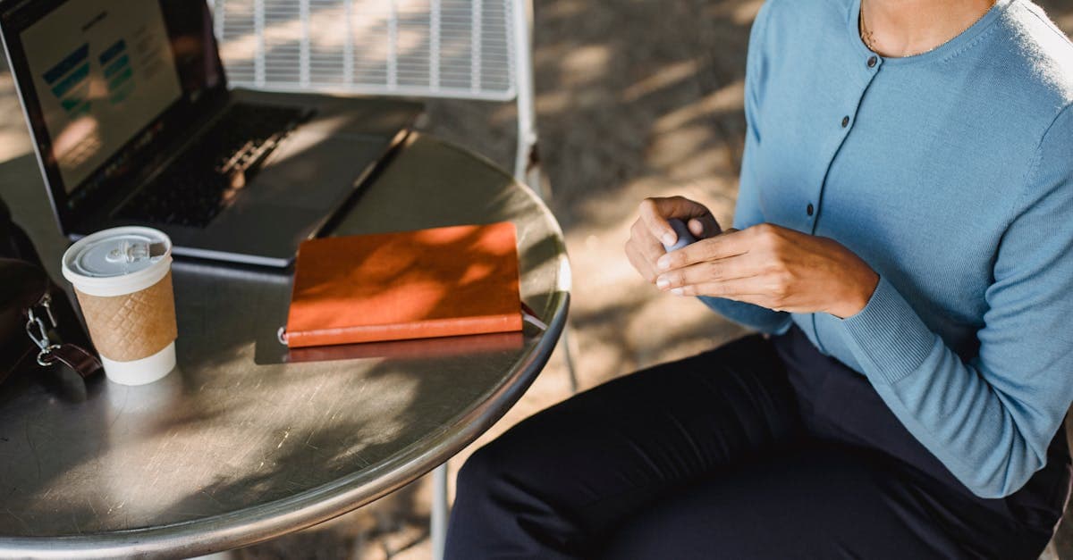 Kvinde arbejder udendørs med laptop og kaffe ved hjælp af en bærbar wifi-router