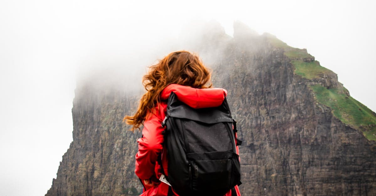 First-time solo traveller sitting before dramatic fog-covered cliffs in the Faroe Islands with a backpack