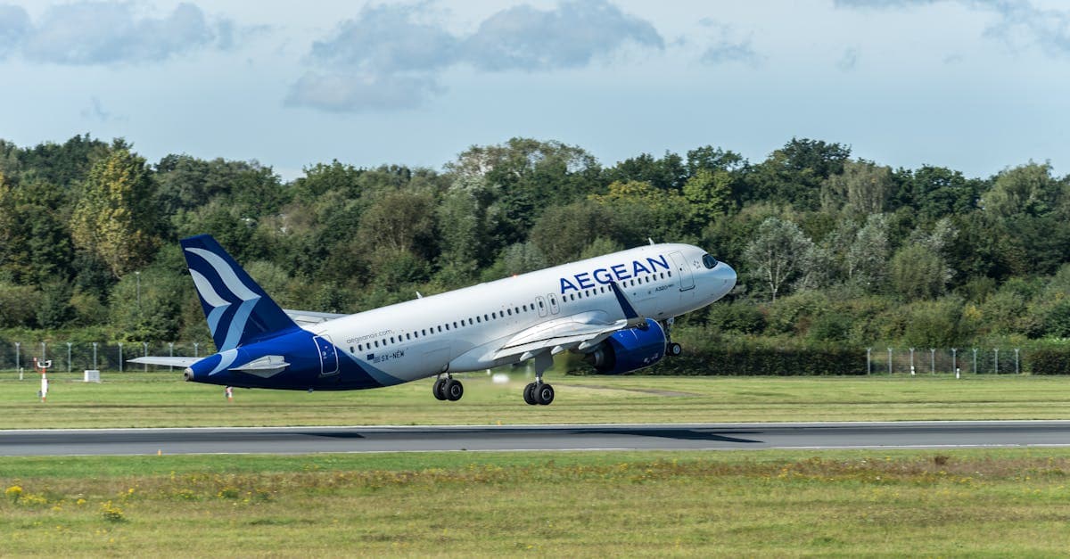 Aegean Airlines Airbus A320 taking off from Hamburg airport with lush greenery in the background.