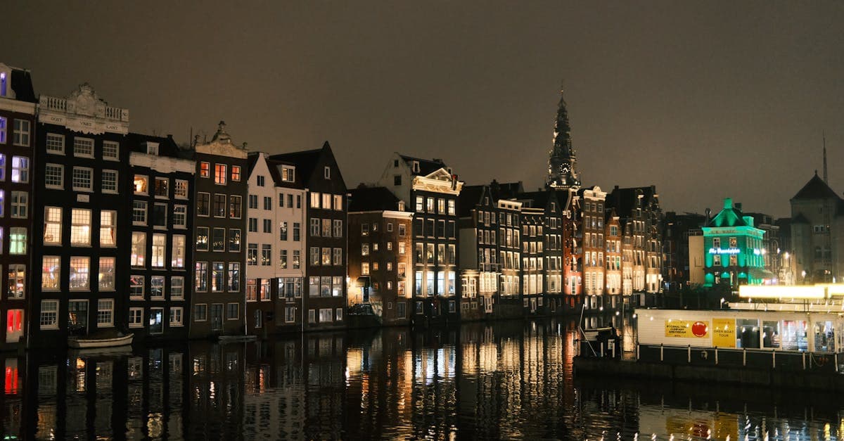 Illuminated Amsterdam canal houses reflected on water at night, showcasing unmissable things to do in amsterdam