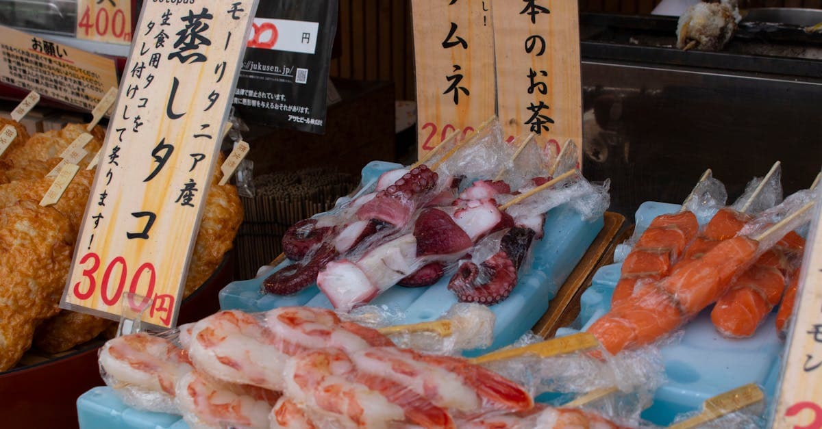 Espetinhos coloridos de frutos do mar expostos em mercado japonês, respondendo o que comer no japão.