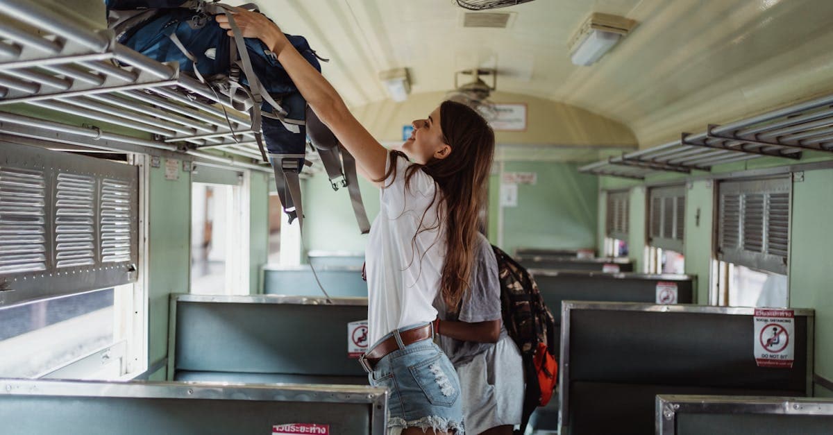 Solo female traveller safely stowing her backpack on the overhead rack of a clean, empty Japanese train carriage