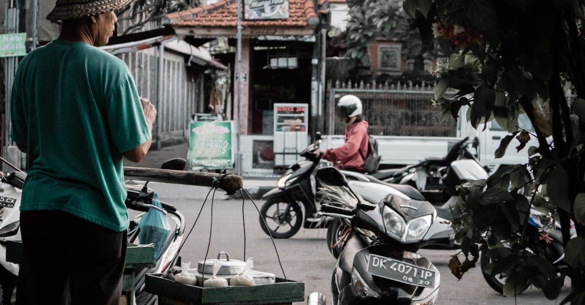 Vendedor ambulante en la calle de Bali atendiendo a motoristas, transporte local para moverse por la isla