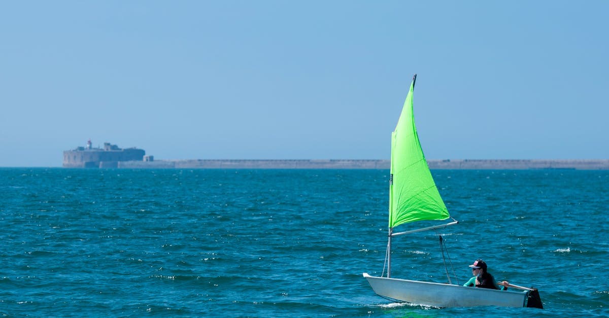Persona navegando en un velero de vela verde cerca de Querqueville, Normandía, en un destino seguro para viajar sola.