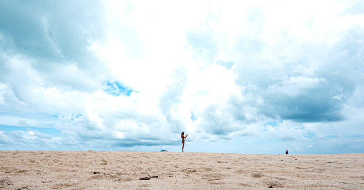 Turysta spaceruje po opustoszałej plaży pod zachmurzonym niebem: kiedy nie lecieć do tajlandii.