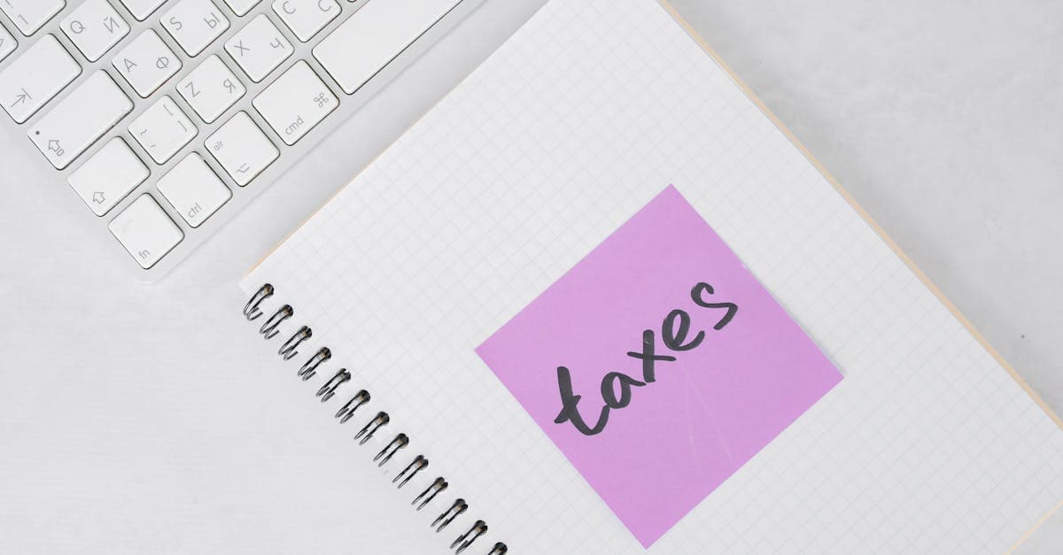 Overhead view of notebook with taxes sticky note beside keyboard, NZ tax planning for Bali travel eSIMs