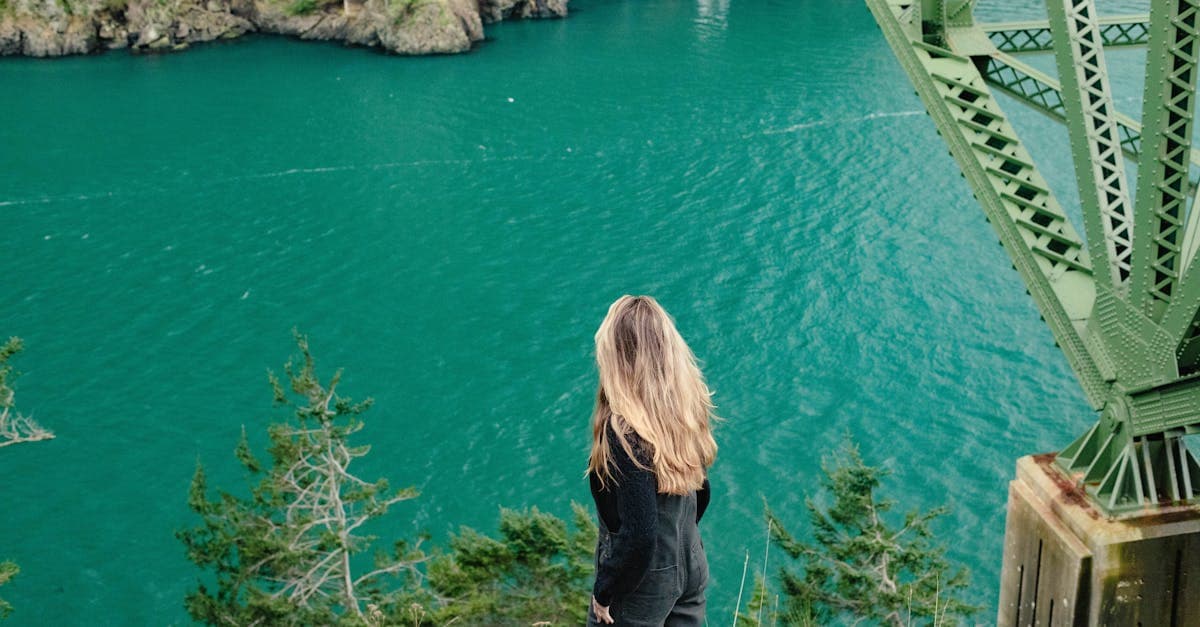 Woman overlooking a tranquil ocean from a rugged green cliff, capturing the true cost of solo travel in 2026.