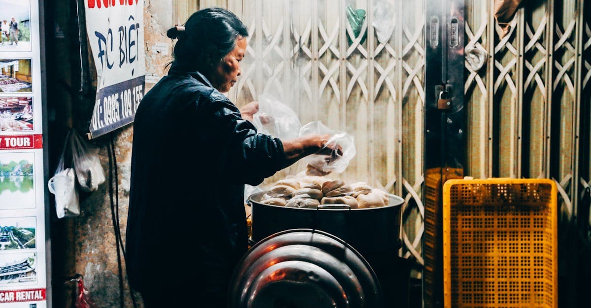Marchande préparant des banh bao à la vapeur dans une rue gastronomique de Hà Nội