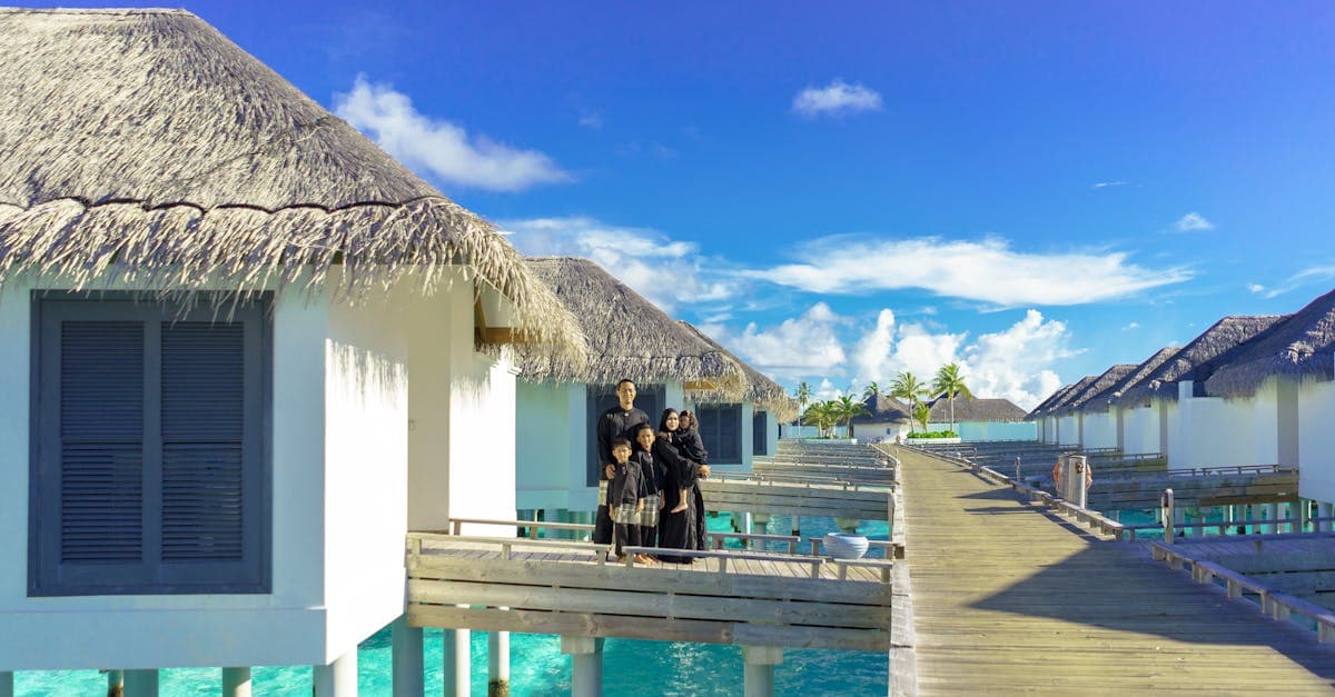 Family walking along a sunny resort boardwalk with overwater bungalows, enjoying their Maldives travel eSIM connected holiday