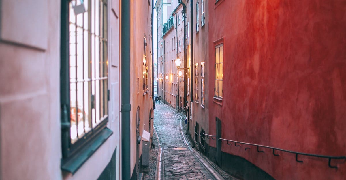 Smal kullerstenspassage i Gamla Stan med upplysta fönster i skymningen under en walking tour