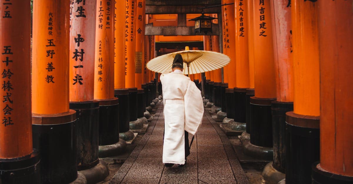 Visitor in traditional attire walking through the iconic vermilion torii gates at Fushimi Inari Shrine, Kyoto