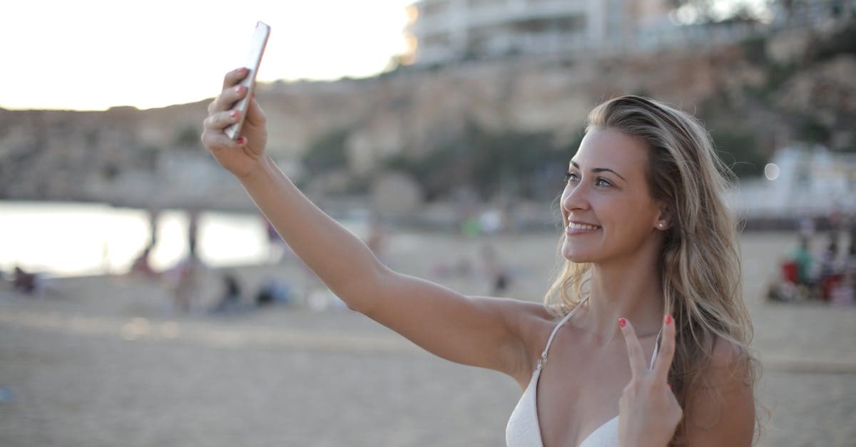 Woman on a Spanish beach taking a selfie and relying on esim spain for holiday mobile coverage