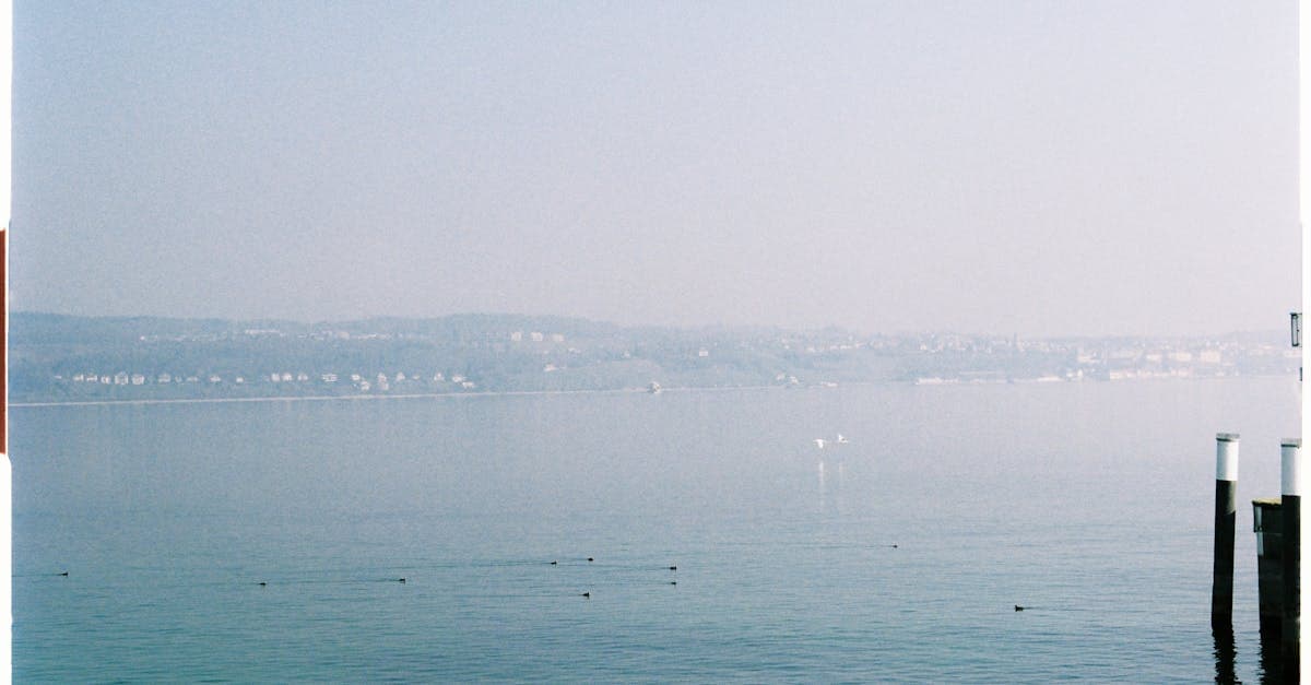 Serene landscape of Lake Constance with distant view of Meersburg, Germany in a calming blue tone.