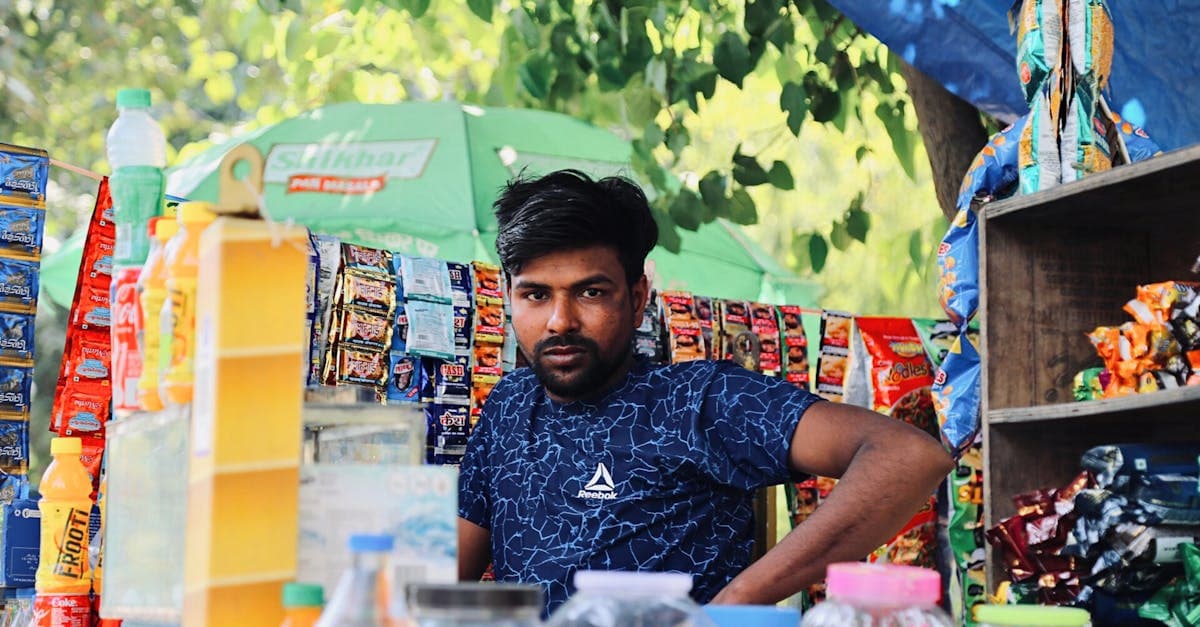 Puesto callejero de gastronomía india con vendedor rodeado de snacks y bebidas tradicionales