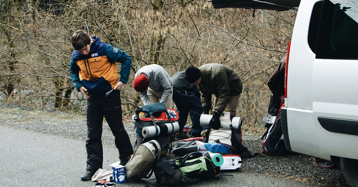 Group of hikers loading outdoor adventure gear beside their vehicle on a scenic New Zealand road
