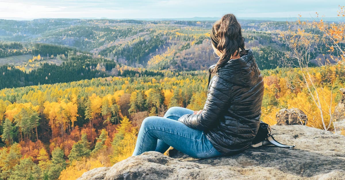 Frau beim Alleinreisen bewundert herbstliche Sächsische Schweiz mit leuchtenden Laubfarben und Waldpanorama