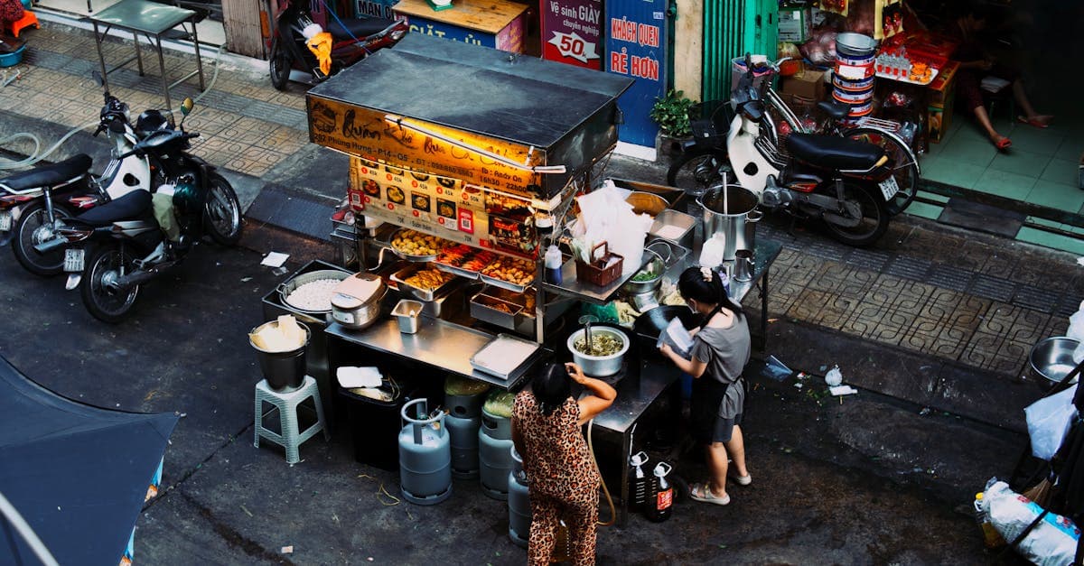 Twee vrouwen bereiden gerechten aan een drukke Vietnamese streetfoodkraam in de avond.