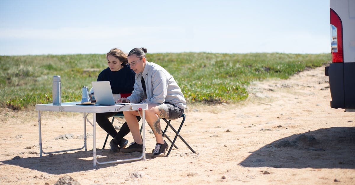Two adults working on laptops outdoors in Portugal, evaluating whether a portable wifi hotspot is worth it