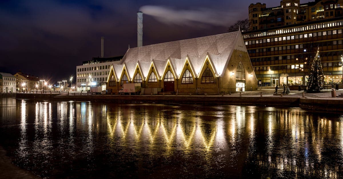 Upplyst fiskehall med reflektioner i vattnet i Göteborg på natten, ett must för things to do in gothenburg