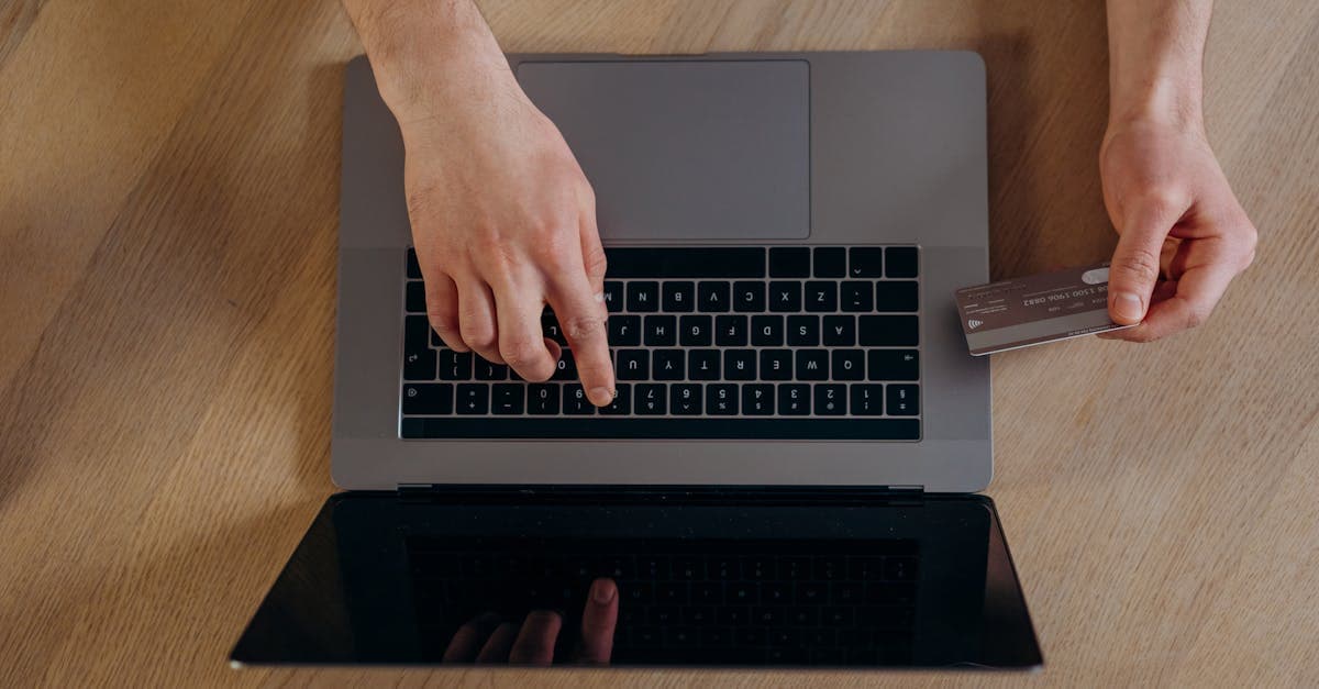 Mains utilisant un ordinateur portable pour comparer une carte SIM physique et une eSIM pour l'Europe