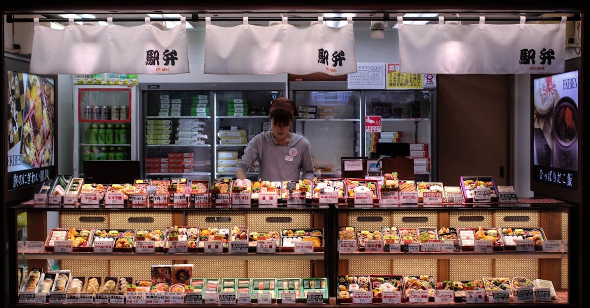 Woman arranging fresh bento boxes in a Tokyo shop, ideal for exploring Japan's local food scene