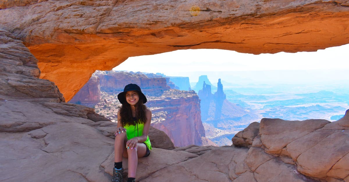 Vrolijke vrouw poseert bij een natuurlijke rotspoort, symbool voor de vrijheid van solo reizen.
