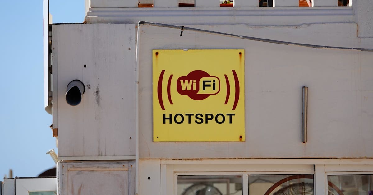 Public WiFi hotspot sign on a building facade in Cala Rajada, Spain, showing when tethering makes sense