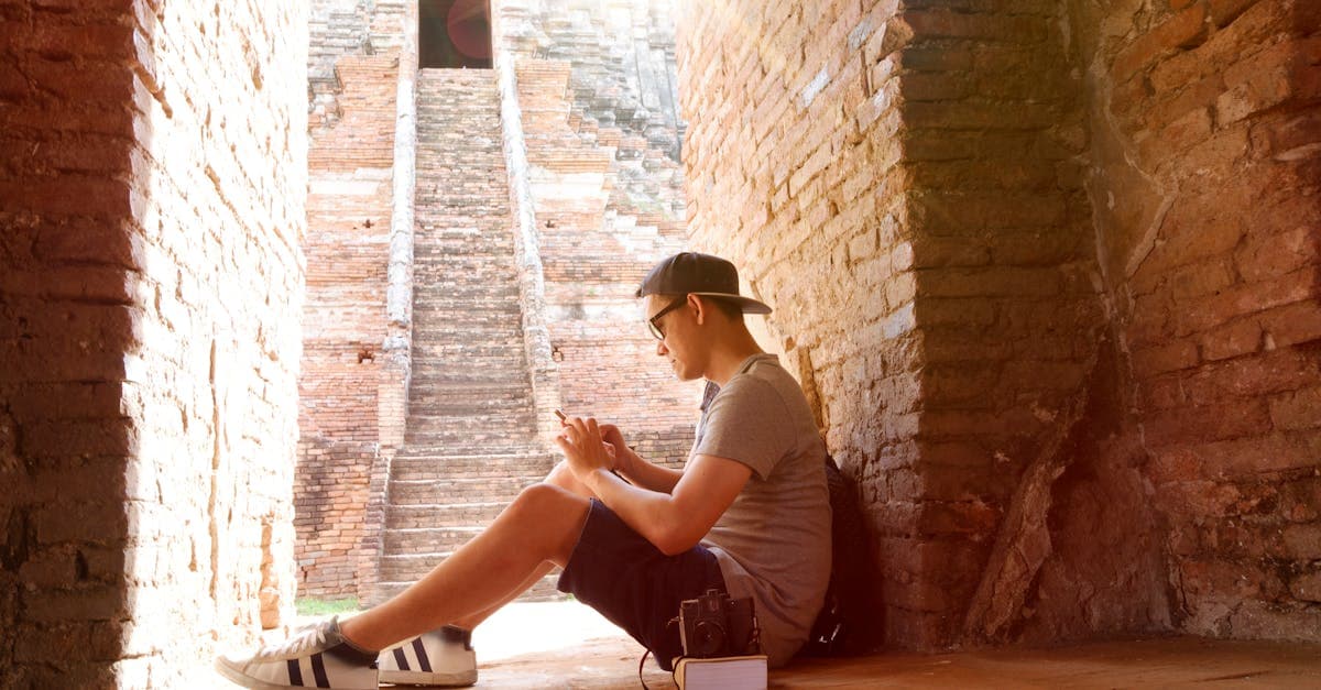 Young traveller sitting on steps at historic brick ruins, using a travel eSIM to stay connected abroad affordably