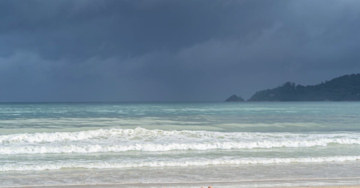 Sunbathers on a Phuket beach under moody clouds, typical of thailand weather in shoulder season